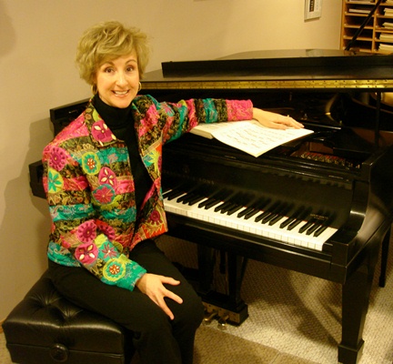 Jacqueline Ryz seated at one of the two Steinway grand pianos in her studio